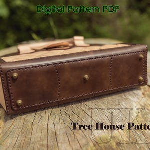 May include: The bottom of a brown leather handbag with a light brown quilted top. The bag has a stitched design and metal accents. The text "Tree House Patterns" is visible on the wooden surface below the bag.