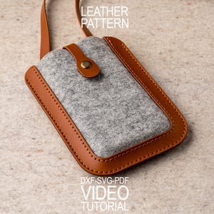 May include: A gray felt phone case with a brown leather frame and strap. The case has a button closure and the text "LEATHER PATTERN" and "DXF-SVG-PDF VIDEO TUTORIAL".