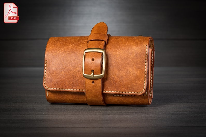 May include: A brown leather wallet with a strap and buckle closure. The wallet has a distressed look and is stitched with white thread.