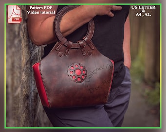 May include: A brown leather handbag with a red lining and a circular cutout design. The bag has a top handle and a  "Designed By Tree House" label.