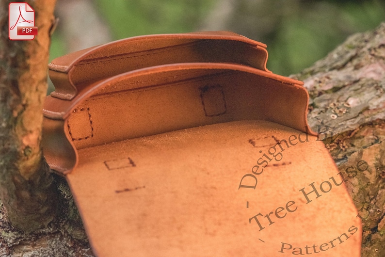 May include: A brown leather pouch with two compartments, each with a flap closure. The pouch is open and the inside is visible. The pouch is designed for carrying small items.