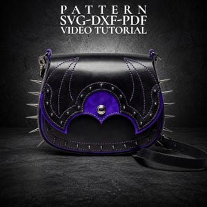 Pode incluir: Bolsa de ombro de couro preta com detalhes roxos e pontas prateadas. A bolsa apresenta costuras decorativas e um painel de camurça roxa. O texto na imagem diz "PATTERN SVG-DXF-PDF VIDEO TUTORIAL".