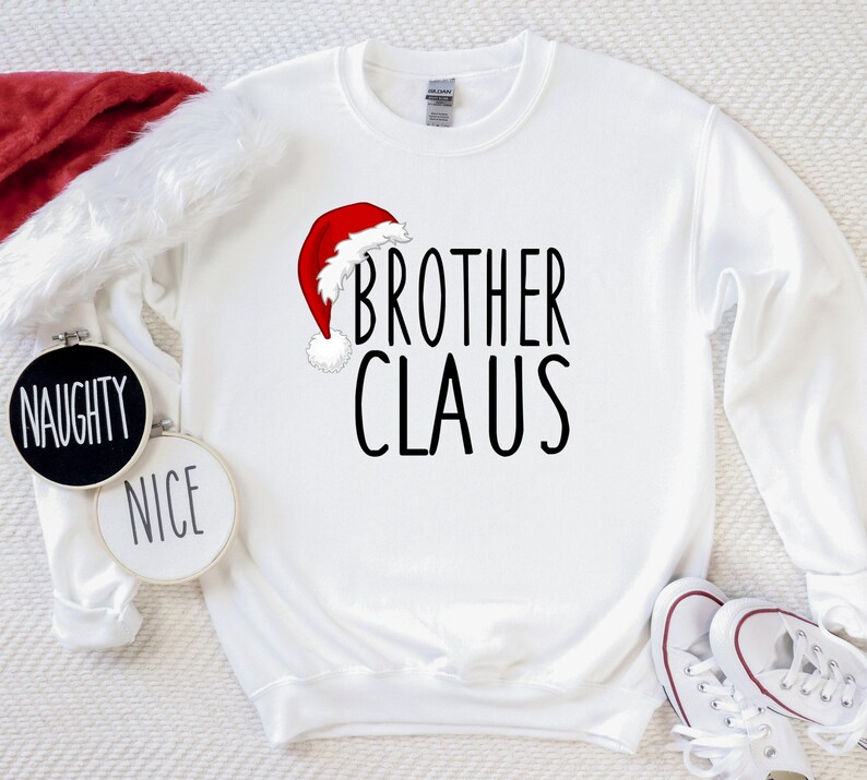May include: White Christmas sweatshirt with a red Santa hat graphic and the text "Brother Claus".