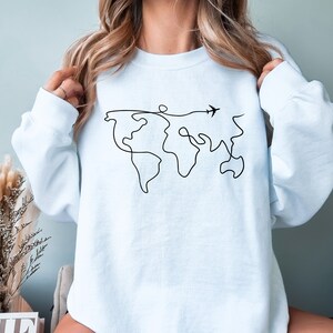 May include: A light blue sweatshirt with a black line drawing of the world and a small airplane flying above it.
