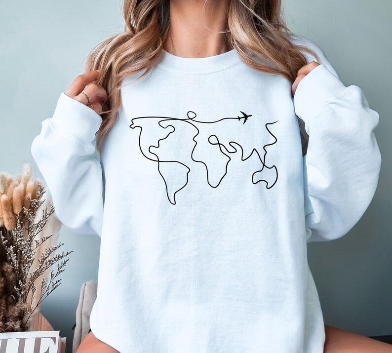 May include: A light blue sweatshirt with a black line drawing of the world and a small airplane flying above it.