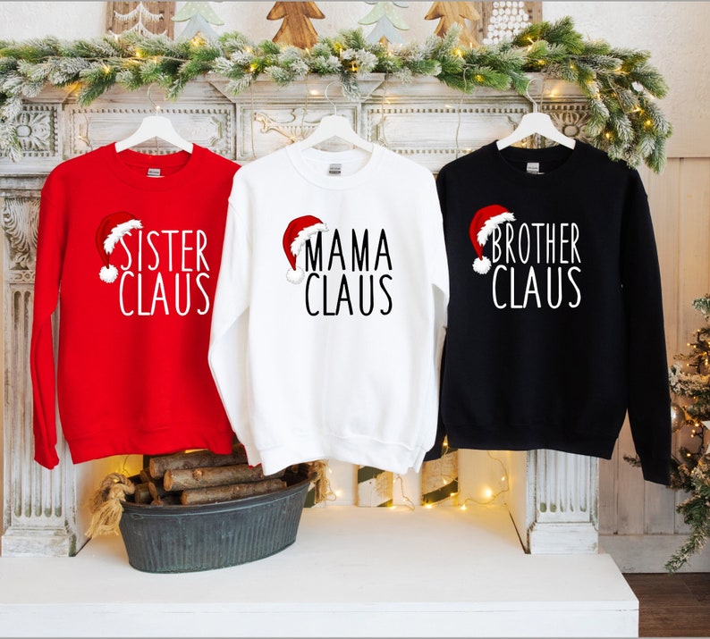May include: Three red, white, and black long-sleeved sweatshirts with a Santa hat graphic and the text "Sister Claus", "Mama Claus", and "Brother Claus".