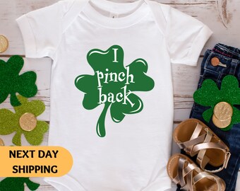 May include: White baby onesie with a green shamrock and the text "I pinch back".