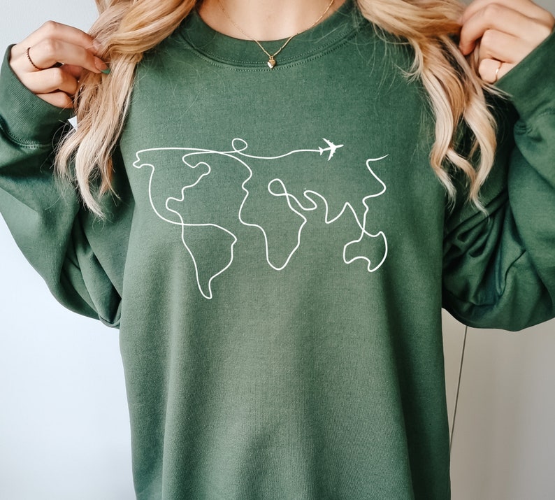 May include: A dark green sweatshirt with a white outline of the world and a small airplane flying above it.