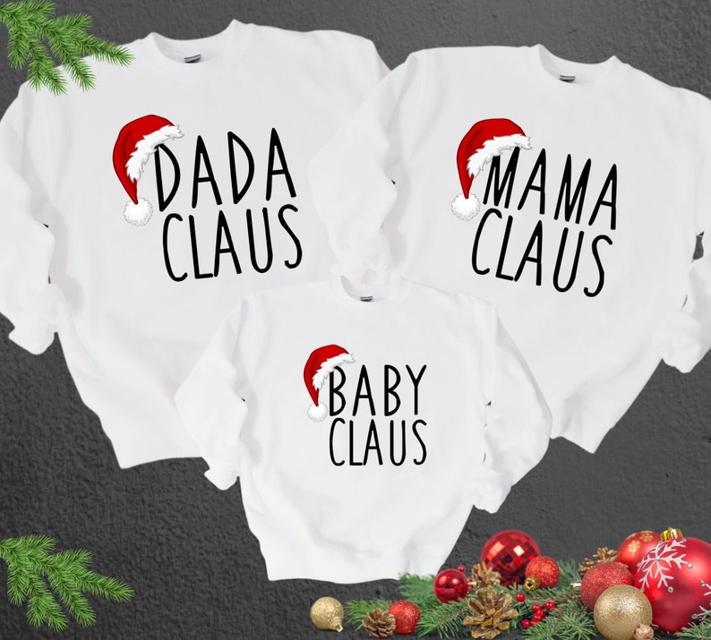 May include: Three white Christmas sweaters with red Santa hats and black text. The sweaters say "Dada Claus", "Mama Claus", and "Baby Claus".