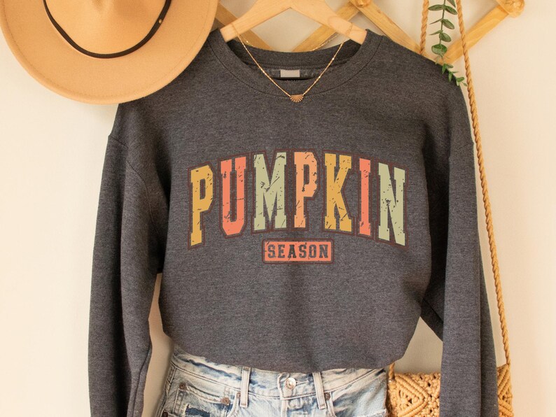 Może przedstawiać: Szara bluza z nadrukiem w stylu vintage z napisem "Pumpkin Season" w kolorach tęczy.