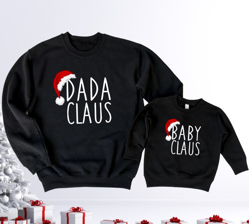 May include: Black Christmas themed sweatshirts with the text "Dada Claus" and "Baby Claus" in white lettering. Each sweatshirt features a red Santa hat graphic.