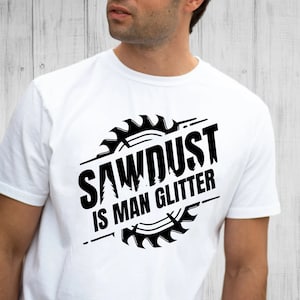 May include: White t-shirt with a black graphic of a saw blade with the text "Sawdust is man glitter".
