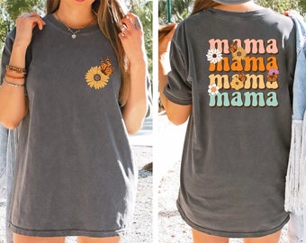 May include: A dark gray t-shirt with a butterfly and flower design on the front and the text "mama mama mama mama" in a retro font with flowers on the back.