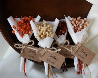 May include: Four small bouquets of dried flowers wrapped in white tissue paper with twine and a brown card tag. The tags are labeled "Hailey Bridesmaid", "Audrey Bridesmaid", "Maid of Honor", and "Hailey Bridesmaid".