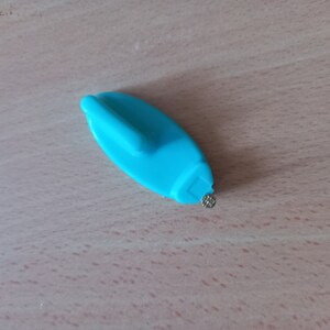 May include: A blue plastic tool with a small metal point, designed for removing price tags from items.