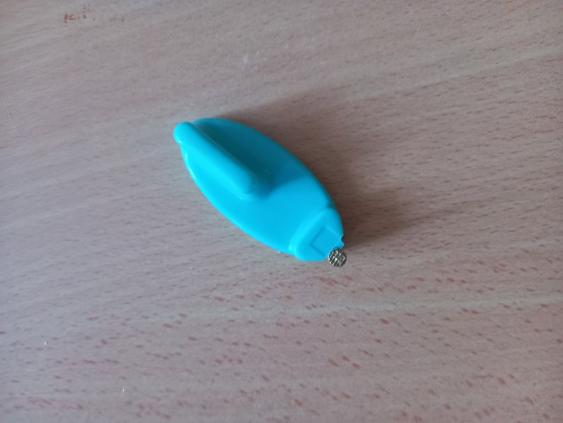 May include: A blue plastic tool with a small metal point, designed for removing price tags from items.