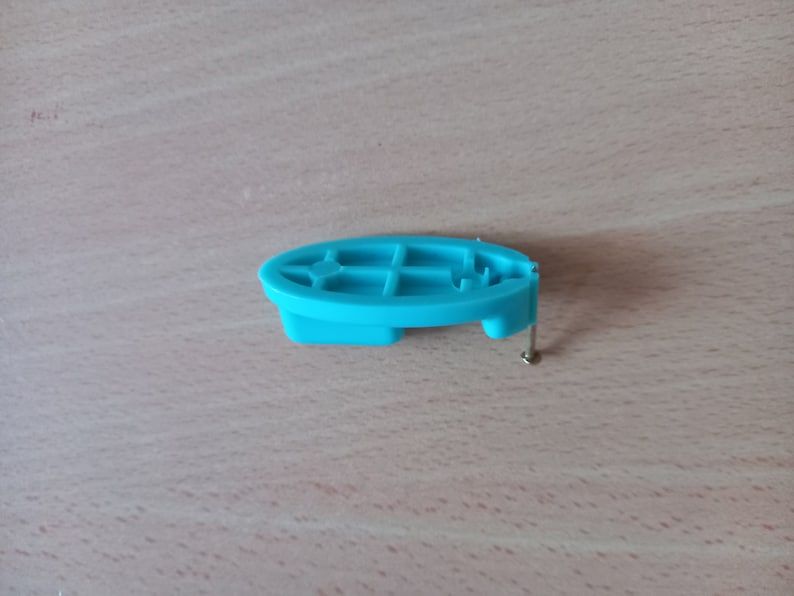 May include: A light blue plastic piece with a grid pattern and a small metal screw. The piece is designed to be attached to a surface.