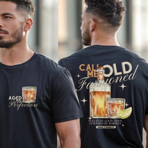 Könnte beinhalten: Schwarzes T-Shirt mit Whiskey-Motiv. Auf der Vorderseite befindet sich eine Grafik eines Whiskeyglases mit dem Text "AGED TO Perfection". Auf der Rückseite sind eine Whiskeyflasche und ein Glas mit den Worten "CALL ME OLD Fashioned" abgebildet. Das Shirt enthält auch den Text "FUELED BY GOOD TIMES, POWERED BY WHISKEY."