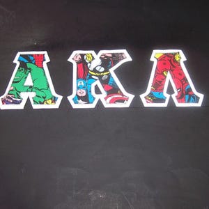 May include: The letters "AKA" are displayed in a comic book style on a black background. Each letter is filled with a different superhero image and outlined in white. The letter "A" features the Hulk, Thor, and Spider-Man.