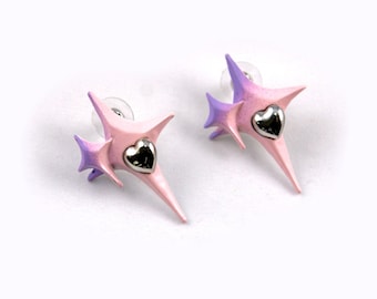 Può includere: Un paio di orecchini rosa e viola con un ciondolo a forma di cuore argentato. Gli orecchini hanno la forma di una stella con una punta appuntita.