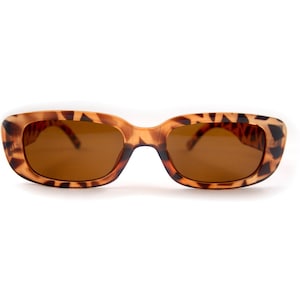 May include: Rectangular sunglasses with a tortoiseshell pattern. The frames are a mix of brown and tan, with dark brown lenses. The sunglasses are set against a white background.