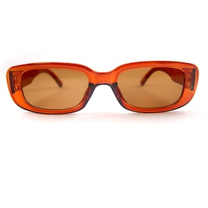 May include: Orange tinted rectangular sunglasses with a brown frame.