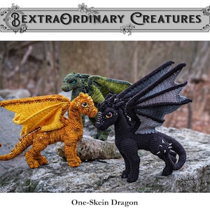 May include: Three crocheted dragon toys, one black, one orange, and one green, are posed on a rock. The black dragon has a spiky tail and wings. The orange dragon has a yellow tail and wings. The green dragon has green wings. The text "One-Skein Dragon" is below the dragons.
