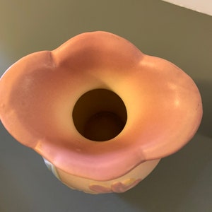 May include: A pink ceramic vase with a scalloped rim and a floral design. The vase is empty and ready to be filled with flowers.