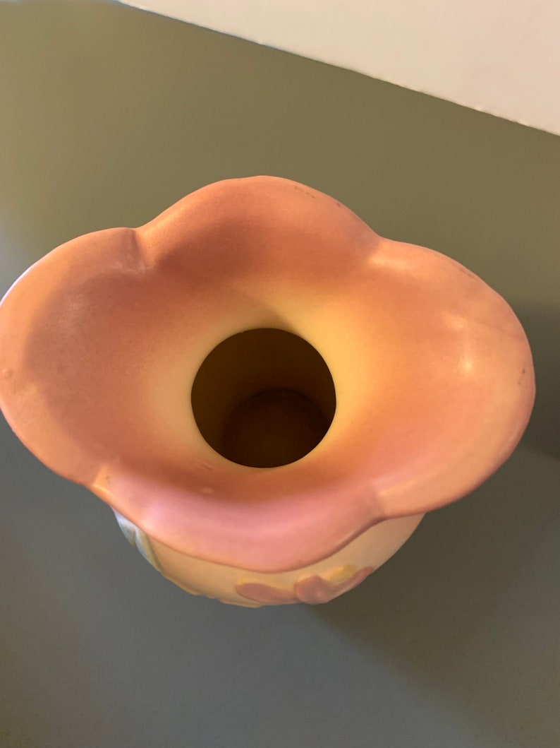 May include: A pink ceramic vase with a scalloped rim and a floral design. The vase is empty and ready to be filled with flowers.
