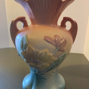 May include: A vintage, hand-painted, pink, yellow, and blue ceramic vase with two handles and a floral design. The vase has a scalloped rim and a flared base.