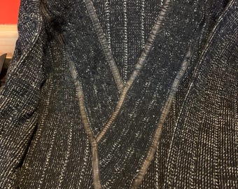 May include: A black and white knit sweater with a V-neck design. The sweater features vertical stripes and dark gray leather-like accents along the neckline. The ribbed knit cuffs and hem complete the design.