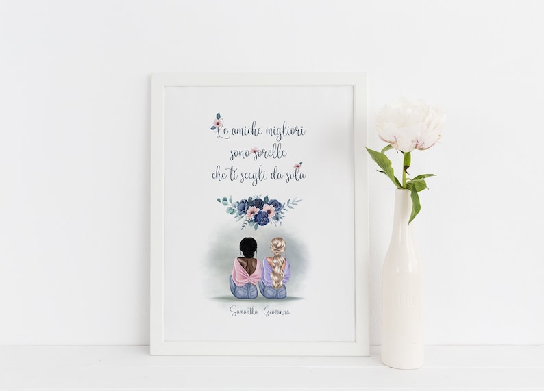 May include: A framed art print featuring an illustration of two women with the text "Le amiche migliori sono sorelle che ti scegli da sola." The print is in a white frame and includes a floral design. A white vase with a flower is next to the frame.