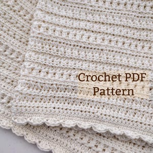 Pode incluir: Um cobertor de crochê na cor creme com uma borda festonada. O cobertor está dobrado ao meio e o texto "Crochet PDF Pattern" é visível na imagem.