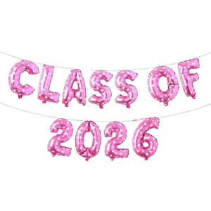 May include: Pink foil balloons spelling out "CLASS OF 2026" with white polka dots. The balloons are strung together on a thin string, perfect for a graduation party or celebration. The letters and numbers are large and easy to read.