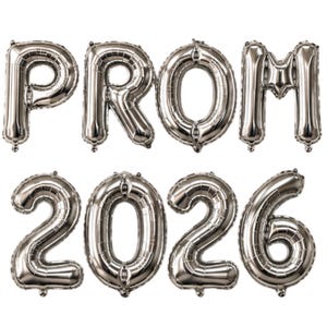 May include: Silver foil balloons spelling out "PROM 2026". The balloons are inflated and arranged in two rows, with "PROM" on top and "2026" below. The balloons are metallic and reflective.