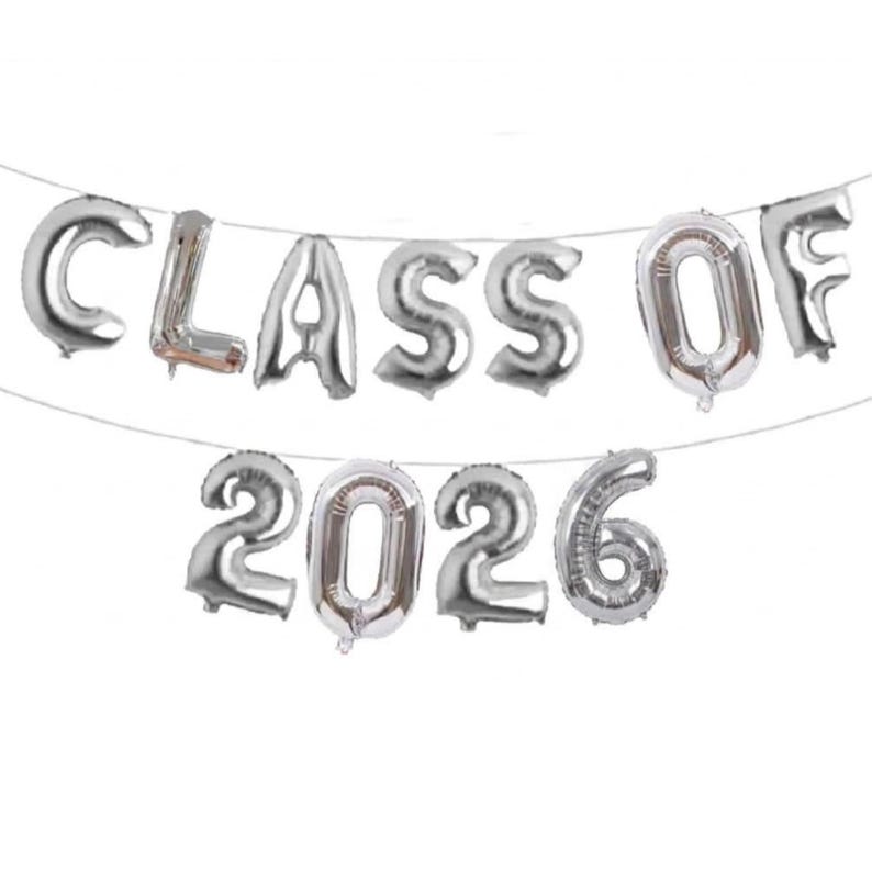 May include: Silver foil balloons spelling out "CLASS OF 2026" strung on a thin white string. The balloons are inflated and have a metallic sheen. Ideal for a graduation celebration.