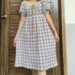 May include: A green and purple gingham crochet dress with a square neckline and puff sleeves.
