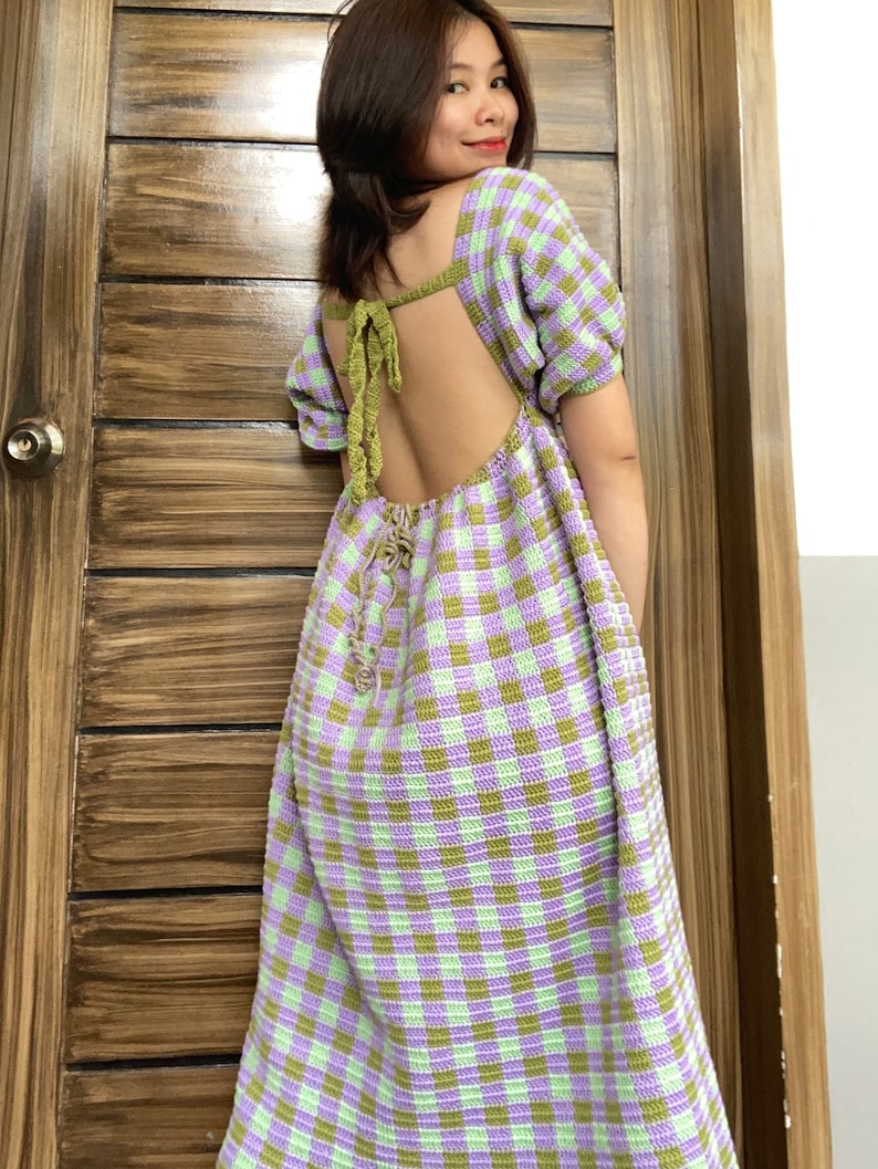 May include: A green and purple gingham crochet dress with a low back and a tie detail. The dress has short sleeves and a loose fit.