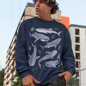 May include: A navy blue sweatshirt with a pattern of whale sharks and seaweed. The sweatshirt has long sleeves and a crew neck.