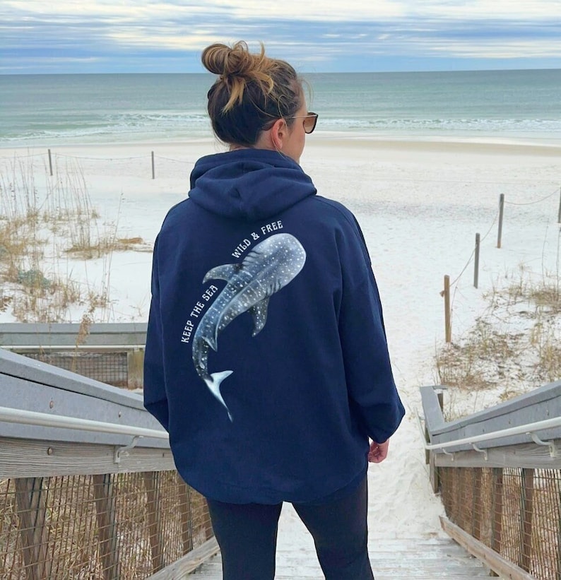 May include: A navy blue hoodie with a white whale shark graphic on the back. The graphic includes the text "Keep the Sea Wild & Free".