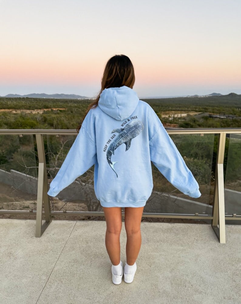 May include: A light blue hoodie with a graphic of a whale shark on the back. The text "Keep the Sea Wild & Free" is printed on the hoodie.
