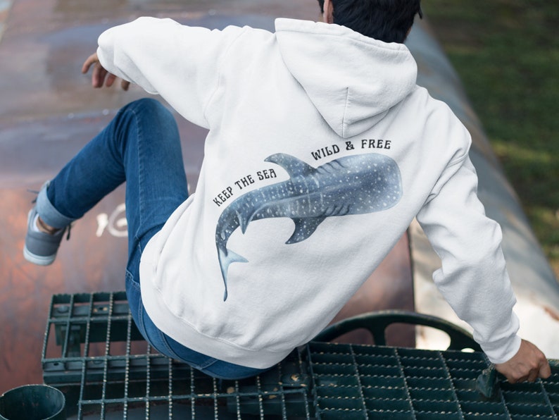 May include: White hoodie with a blue whale shark graphic on the back. The text "Keep the Sea Wild & Free" is printed on the hoodie.