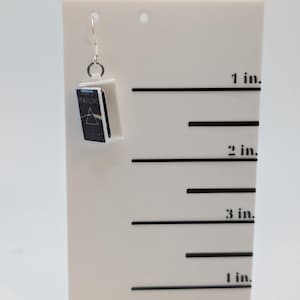 a pair of earrings sitting on top of a white stand