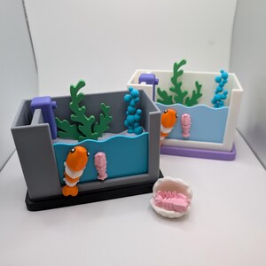 May include: Two miniature aquariums with blue water, orange and pink shrimp, green and blue plants, and a white shell with pink shrimp inside.