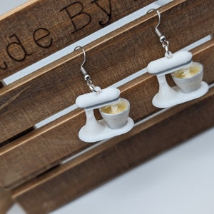 May include: A pair of white and silver stand mixer earrings. The earrings are made of polymer clay and have a realistic look.
