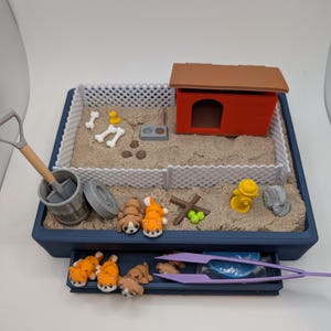 May include: A blue sandbox playset with a red dog house, a fence, a fire hydrant, a shovel, a trash can, bones, and poop. There are also several small orange and brown dogs in the drawer.