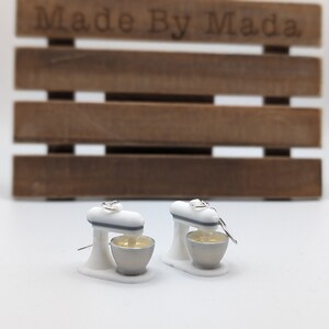 May include: A pair of white and gray miniature stand mixer earrings. The earrings are made of polymer clay and have a silver hook.