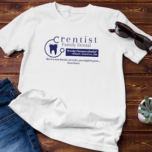 May include: White t-shirt with a blue graphic of a dentist's logo and the text "Crentist Family Dental" and "It's why I became a dentist! -Robert Crentist, DDS We're a new dentist, we're far, you might be gone... three hours"