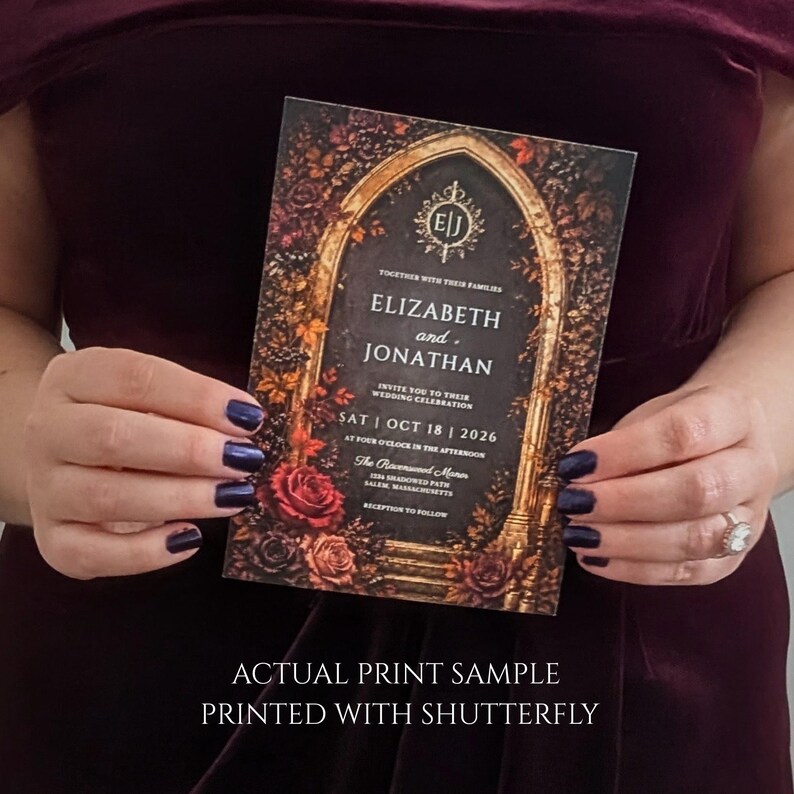 May include: A rectangular wedding invitation card featuring a dark gothic archway design surrounded by deep red and orange autumn roses and foliage. The text reads: Elizabeth and Jonathan, Sat Oct 18 2026, The Ravenswood Manor, Salem, Massachusetts.