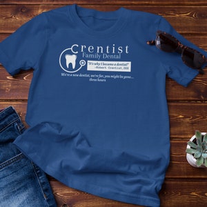 May include: A blue t-shirt with a white graphic design that says "Crentist Family Dental" and includes a quote: "It's why I became a dentist!" -Robert Crentist, DDS. The graphic also includes a tooth and a stethoscope.